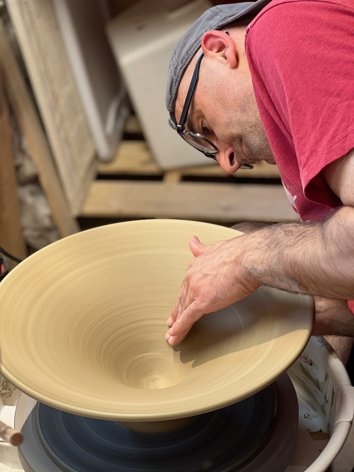 Hands shaping a wide bowl on the potter's wheel
