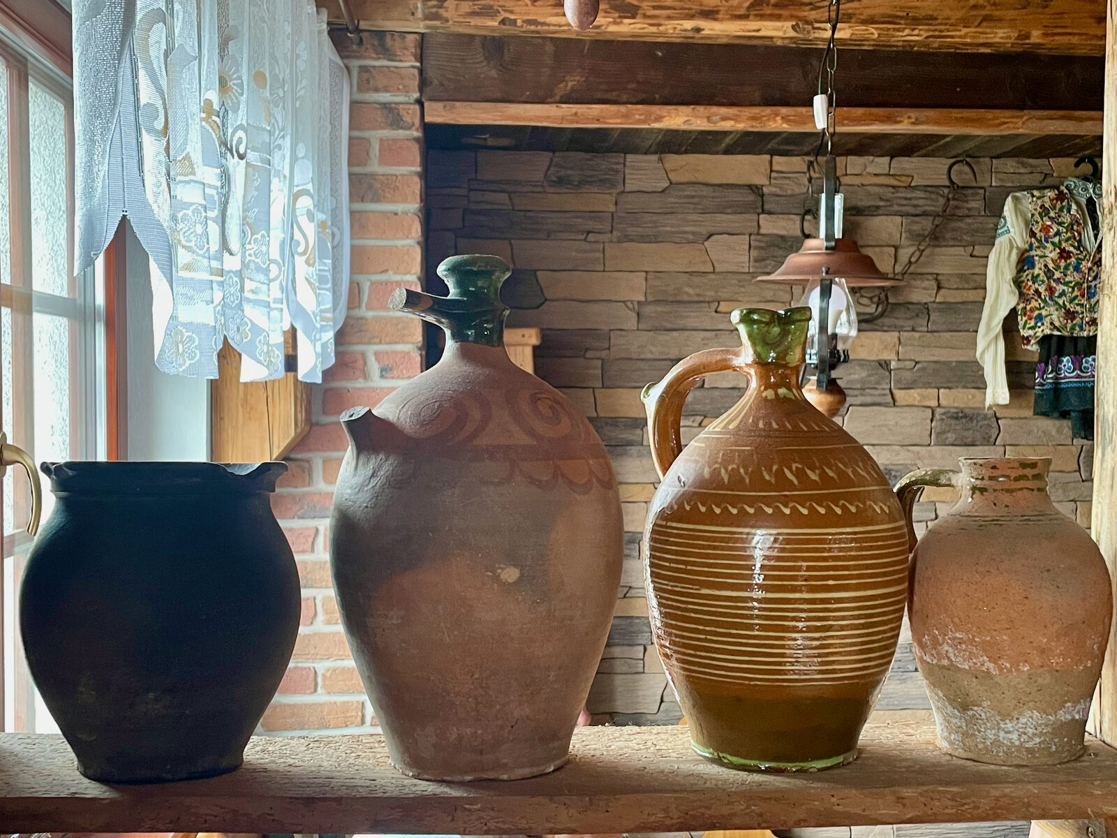 Traditional Slovak earthenware and glazed jugs on a wooden shelf